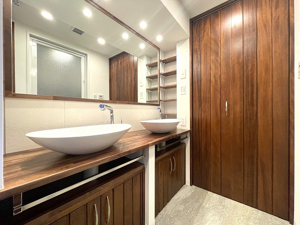 シェトワ白金台_サニタリールームの写真 お部屋全体と統一されたデザインのパウダールームは、朝の慌ただしい時間もスムーズにしてくれる気持ちのいい空間です。大きなワイドミラーと、並んで使える2つの丸形ボウルが家族にちょうど良い距離感をつくり、忙しい時間帯のストレスを軽減。収納もたっぷりあるため、生活感が出やすい水回りもすっきり保てます。