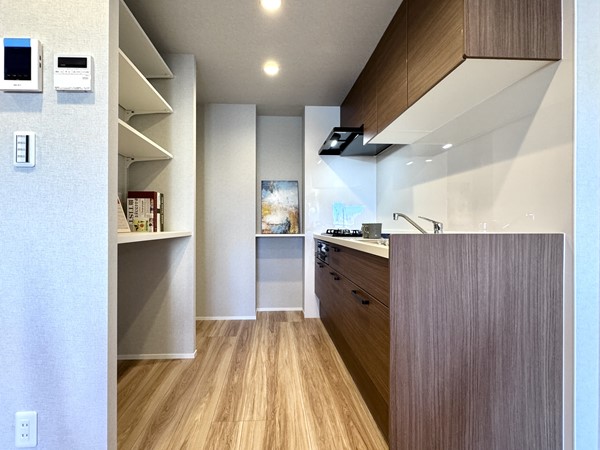 朝日中目黒マンション_システムキッチンの写真 キッチンは壁付けのレイアウトで、落ち着いてお料理に向き合えるつくりです♪ 背面には大きなオープン収納があり、調理器具やキッチン家電もすっきり収まりそう。冷蔵庫は背面収納の右側に配置でき、動線もスムーズです◎ さらにコンロ左手の壁には小さなカウンターを完備。よく使う調味料やツールを手の届く場所に置ける、使い勝手の良いキッチンでした。