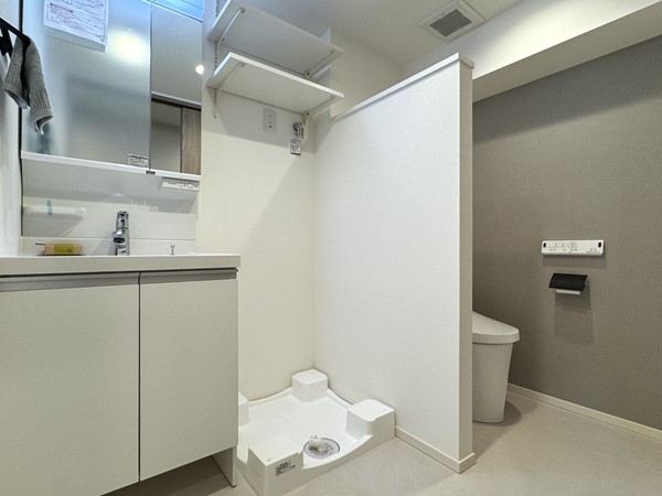 朝日中目黒マンション_サニタリールームの写真 洗面化粧台・ランドリー・トイレが1室にまとまったサニタリールーム。トイレは個室ではなく、間仕切り壁でさりげなく目隠しされた半独立タイプです♪ 日本では少々珍しい造りですが、開放感があり、お掃除がしやすいのが特徴です。 使用後はドアノブに触れることなく、すぐに手を洗えるため、慣れると日々の使い勝手の良さもしっかり感じられるはず◎