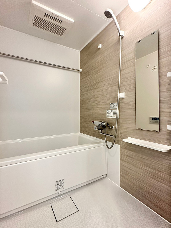 バスルーム　ノア新宿1号館 木目調のブラウンのパネルが特徴のバスルーム。浴室乾燥機が備わっているので、天候を気にせずお洗濯が可能です。バスタブには追い焚き機能もあり、いつでも温かいお風呂に浸かっていただけます。