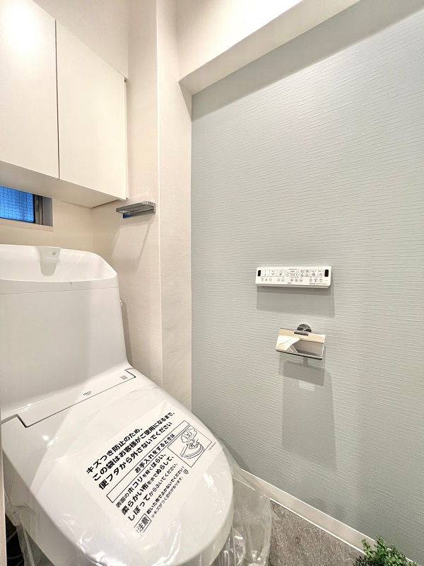 トイレ　目白台コーポ 心を落ち着かせる効果のあるパステルカラーのブルーが印象的なトイレは、清潔感が溢れています。温水洗浄便座が備わり、機能性にも満足していただけますよ。トイレットペーパーなどの備品は吊戸棚へ収納し、スッキリとした空間を保ちましょう。