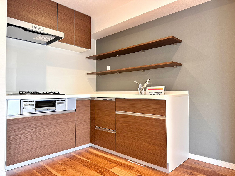 エンゼルハイム東大島第1　キッチン グレーのアクセントクロスが落ち着いた印象を与えてくれるキッチン。L字型の壁付きタイプで、ワークトップの広さが特徴です。棚には常温保存できる調味料などを置けば、使う時にすぐに取り出すことができ便利。
