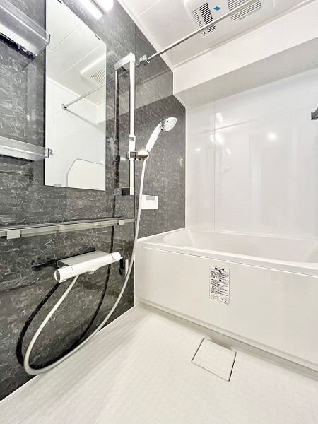 目黒グリーンコープ　バスルーム 大理石調の壁が目を引く、格好良いバスルームです。床は凹凸がある造りのため、転倒のリスクを抑えられますね。追い焚き機能があると、時間が経っても適温に温め直すことができます。浴室乾燥機が備え付けられているため、雨の日や花粉の時期にはこちらで洗濯物を乾かしましょう☔