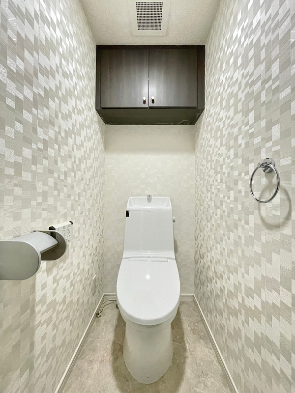 トイレ　ビバリーホームズ西小山 ホワイトを基調とした独立空間の手洗い一体型トイレ。クロスには印象的なデザインが施されていますね。凹凸が少ないためお掃除がしやすく、使用後にすぐ手を洗えるので衛生的ですよ。吊戸棚には予備の備品や掃除用具をしまっておけますね。