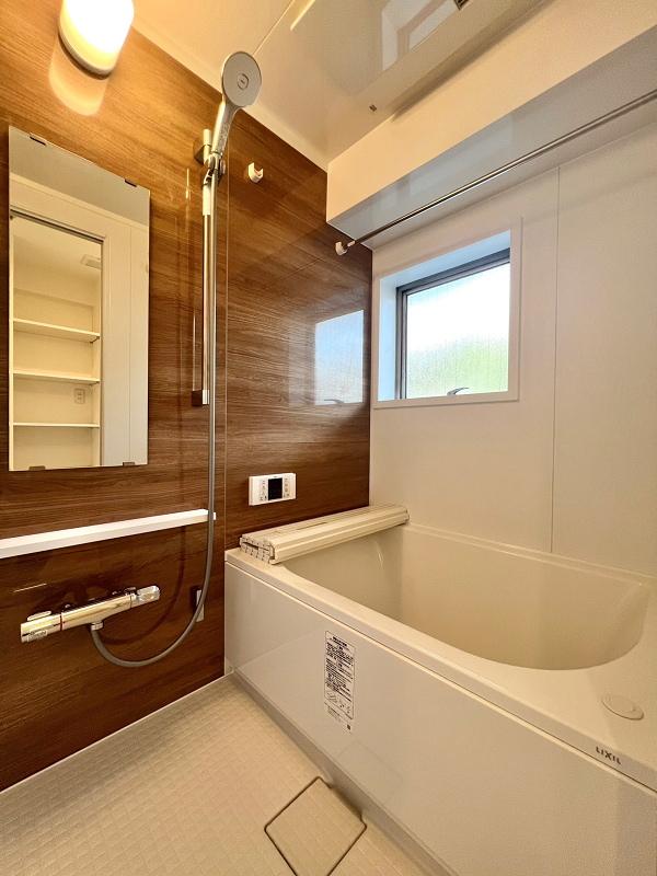 飯田橋ハイツ　バスルーム バスルームは光沢のある木目のパネルを採用し、高級感が漂います。窓が備わっているので換気ができ、水回りの天敵であるカビの心配がなさそうですよ。追い焚き機能や浴室乾燥機を活用し、毎日快適なバスタイムをお過ごしくださいね。