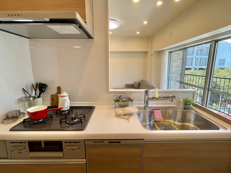 メゾン鳳月　システムキッチン 青いタイルの裏側は使い勝手の良いセミオープンキッチン✧浄水器、食洗器、グリル、3口ガスコンロ、フラットスリムレンジフードを備えています。向かって右側にバルコニーがあるため、キッチン内にもしっかりと風が行き渡りますね。