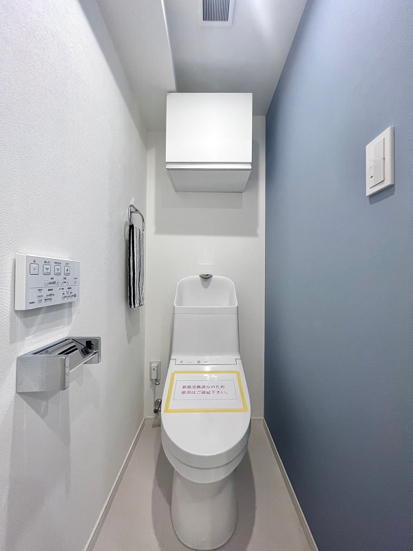 牛込台マンション　トイレ 爽やかなブルーのアクセントウォールが施されたトイレ。気持ちを落ち着かせてくれる色でもあるブルーをセレクトすることで、心地の良い空間に仕上がりました。手洗い一体型のトイレは節水効果が見込まれ、光熱費の節約に繋がりますよ◎