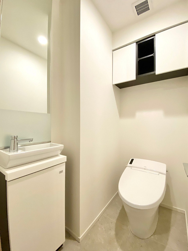 ピアース渋谷WEST　トイレ トイレはかなりゆとりがある独立空間♪白を基調としたモノトーン調のデザインは、シンプルながらも洗練された印象✨独立手洗い場が設置されており、来客時にサニタリールームなどのプライベート空間を見られずに済みますよ。お掃除道具やトイレットペーパーなどの備品は、手洗い場下部や吊戸棚に収納しましょう。