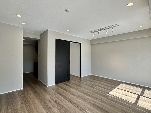 マンション西目黒苑_LDKの写真2 メインルームに足を踏み入れた瞬間、木目調フローリングの温もりが足元から伝わり、自然と深呼吸したくなるような心地よさに包まれます。その中でひと際印象的なのが空間を引き締めるブラックのドア。ナチュラルな素材感にモダンなアクセントが加わり、グッとお洒落に♩