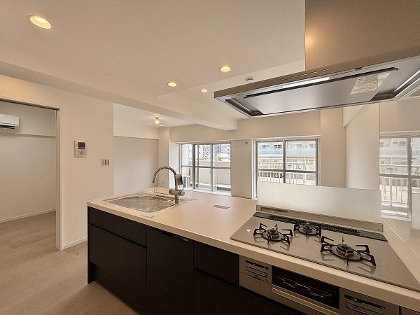 月島ホームズ_広々としたリビングダイニングキッチンの写真 新しく交換されたフルフラットのシステムキッチンは、毎日のお料理をより快適にしてくれます。開放感のあるデザインで、リビングダイニング全体を見渡せるため、小さなお子さまがいても目を離さず安心して作業可能。家事がはかどるだけでなく、家族との時間も自然に感じられる設計になっていますよ。