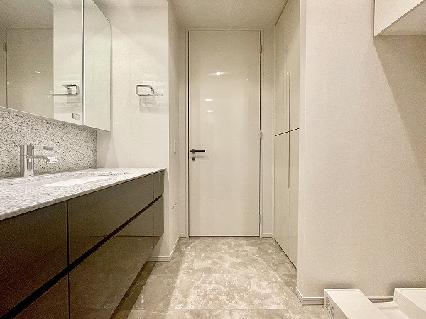 ザ・パークハウス西麻布レジデンス_清潔感のあるサニタリールームの写真 白を基調にした明るく爽やかなサニタリールーム。ミラーキャビネット付きの洗面化粧台はミラーの角度を自由に調整でき、朝の身支度もスムーズにこなせます。洗濯機置き場も同じ空間にあるため、洗濯の下準備や家事の流れが効率的に♩