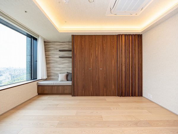 ラ・トゥール千代田_収納豊富な洋室の写真 もう一方の洋室は約7.4帖。折り上げ天井と間接照明が空間に奥行きをもたらし、上質な雰囲気を演出します。クローゼット横にはソファスペースもあり、窓外の景色を眺めながら読書を楽しむのも素敵ですね。