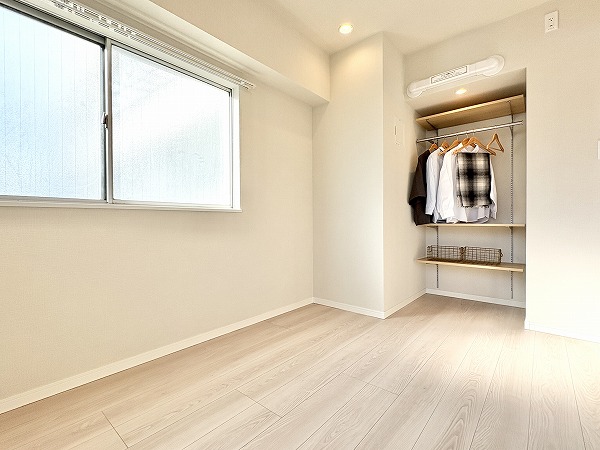 第15宮庭マンション_シンプルな洋室の写真 リビングダイニングに隣接している約4.7帖の洋室は、どんなテイストの家具とも調和する優しい色合いの内装デザイン。特徴的なのは、通気性の良いオープンクローゼットが設置されているところです✦扉が無いため中にあるアイテムを把握しやすく、身支度をスムーズに行えそうですよね。