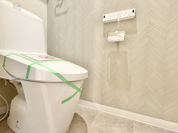 第15宮庭マンション_独立トイレの写真 ヘリンボーン柄のアクセントクロスがオシャレな雰囲気を演出している独立タイプのトイレ。手洗い一体型なので、節水に取り組めるのが嬉しいですよね。上部にはキャビネットが設けられていて、トイレ用品をまとめて収納しておくことができます。