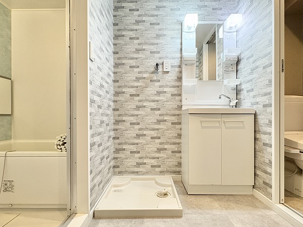 アルム幡ヶ谷_清潔なパウダールームの写真 バスルーム、洗濯機置き場、独立洗面化粧台、トイレがひとまとめに配置された使い勝手の良いサニタリールーム。動線が良いので身支度や家事をスムーズに行うことができ、生活がグッと楽になりそうです✦洗面化粧台の鏡の横には、歯ブラシや化粧品などの細かなものを整理できる複数のラックが付いています。