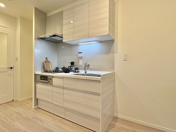 ライオンズプラザ池尻大橋_システムキッチンの写真 キッチンは壁面に沿ったタイプで、リビングへのにおい移りを防ぎつつ、快適に調理可能。収納力が高く、上段と下段にスペースを確保しているため、キッチン周りを整理整頓しやすい設計です。大きめのシンクと3口コンロが日々の料理をサポートします◎