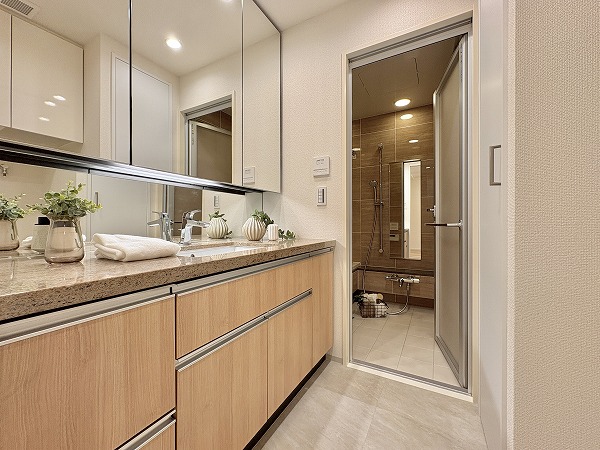 クラッシィハウス世田谷公園_サニタリールームの写真 清潔感あふれるオフホワイトでまとめられたサニタリーは明るく華やかな雰囲気。木目調の洗面化粧台がアクセントに。両サイドのカウンターは朝のメイクやヘアセット、スキンケアの際にも便利◎家族全員が使いやすい工夫が随所に施されています。