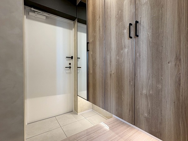 ライオンズマンション西蒲田_玄関廊下の写真 玄関は白を基調とした空間となっております。壁側にはシューズクローゼットが2つもあり、履物はたっぷり保管しておくことができます。シューズクローゼットの下に付いている間接照明が高級感を演出してくれます。