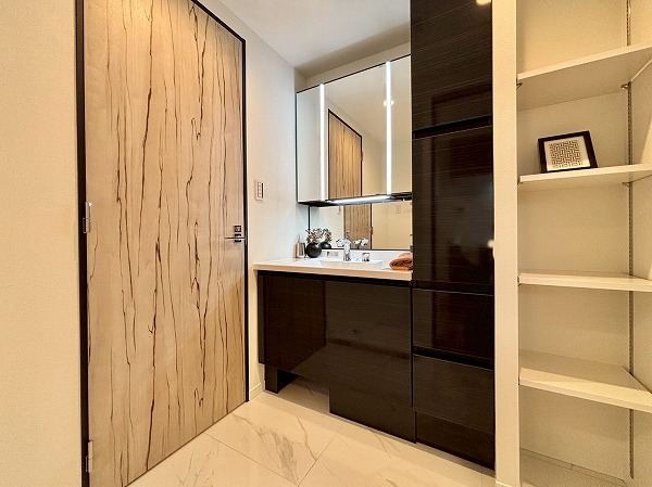 ヒルズ目白台_清潔感のあるパウダールームの写真 モノトーンを基調としたサニタリールームを見てみましょう。玄関廊下と同じ大理石調のタイルが敷かれ、高級感が漂っています。3面鏡の洗面化粧台には縦にLEDライトが2つ設置されていてお顔全体をしっかり照らしてくれます。収納の多さも魅力の1つ。