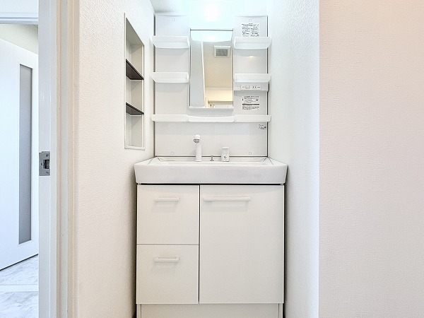 ライオンズマンション松原第2_清潔感のある洗面化粧台の写真 独立洗面化粧台、洗濯機置き場、バスルームが1つの空間にまとめられており、動線の良いパウダールーム。最大の利点は家事や身支度をスムーズに行えること。洗面化粧台の鏡横には複数のラックが備わっていて、化粧品や石鹸などをきれいに収めておくことができます。